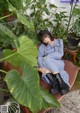 A woman sitting on a chair in front of a plant.