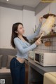 A woman holding a duster in a kitchen next to a microwave.