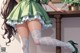 A woman in a green dress and white stockings sitting on a table.