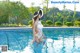 A woman in a white swimsuit and hat standing in a pool.