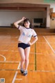 A woman in a white shirt and black shorts standing on a basketball court.