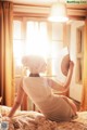 A woman sitting on a bed holding a fan.