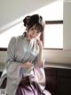 A woman in a kimono sitting on a window sill.