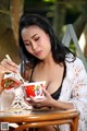 A woman sitting at a table eating a bowl of noodles.