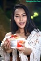 A woman holding a cup of coffee and a sandwich.