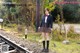 A woman in a school uniform standing on a train track.