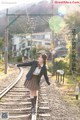 A woman in a school uniform is standing on a train track.