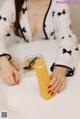 A woman sitting at a table with a bottle of orange juice.