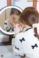 A woman is looking at her reflection in a mirror.