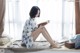 A woman sitting on a window sill reading a book.