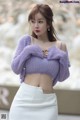 a woman in a purple sweater and white skirt posing for a picture