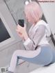 A woman with pink hair is taking a selfie in a bathroom.
