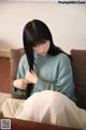 A woman sitting on a couch with long black hair.