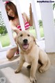 A woman in a pink bikini sitting next to a dog.