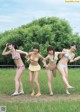 A group of young women in bikinis standing in a field.