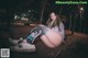 A woman sitting on a bench in a park at night.