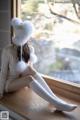 A woman sitting on a window sill wearing a white hat and socks.