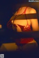 A woman in a red lingerie is reflected in a mirror.