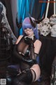 A woman with blue hair and horns sitting on a table.