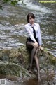 A woman sitting on a rock in the water.