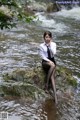 A woman sitting on a rock in the water.