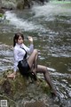 A woman sitting on a rock in the water.