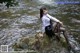 A woman sitting on a rock in the water.