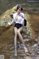 A woman sitting on a rock in the water.