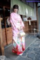 A woman in a pink kimono standing in front of a building.