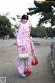 A woman in a pink kimono holding a white cat.