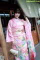 A woman in a pink kimono holding a purse.