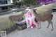 A woman in a kimono sitting on a bench next to two deer.