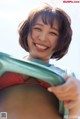 A woman in a red bikini holding a green bag.