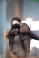 A woman's feet are reflected in a glass table.