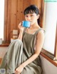 A woman sitting on a window sill holding a cup of coffee.