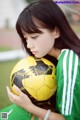 A young woman holding a soccer ball on a field.