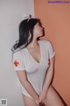 A woman in a white shirt with a red cross on it.