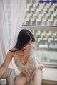 A woman sitting on a couch in front of a window.