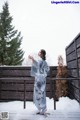 A woman in a blue kimono standing in the snow.