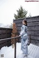 A woman in a blue kimono standing on a wooden deck.