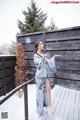 A woman standing on a wooden deck in the snow.