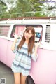 A woman standing in front of a pink and white van.