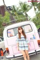 A woman standing in front of a pink and white van.