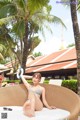 A woman in a bikini sitting on a lounge chair.