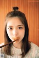 A woman holding chopsticks in front of her mouth.