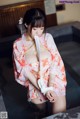 A woman in a pink kimono is tied up to a bathtub.