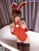 A woman in a red bunny costume posing in a bathtub.