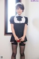 A woman in a maid outfit is posing for the camera.