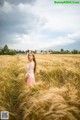 A woman standing in a field of tall grass.