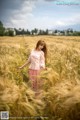 A woman standing in a field of tall grass.